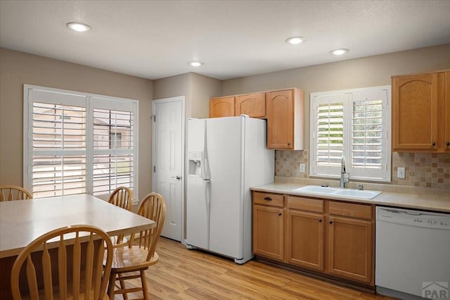 4317 Outlook Blvd Unit D, Pueblo, CO 81008 - kitchen featuring white appliances, a sink, backsplash, light countertops, and light wood-style floors