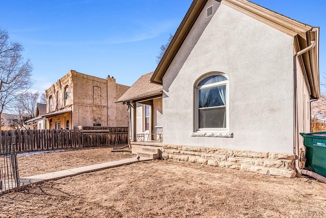 view of side of home with fence and stucco siding