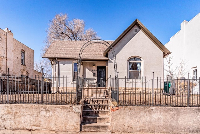 view of front of home featuring a fenced front yard, a gate, a shingled roof, and stucco siding