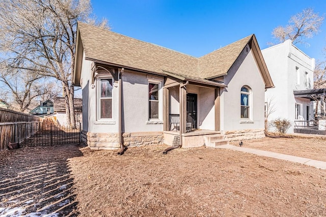 view of front facade featuring a shingled roof, fence, and stucco siding