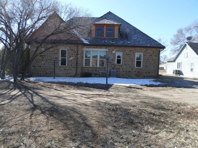 rear view of property with stone siding and central AC