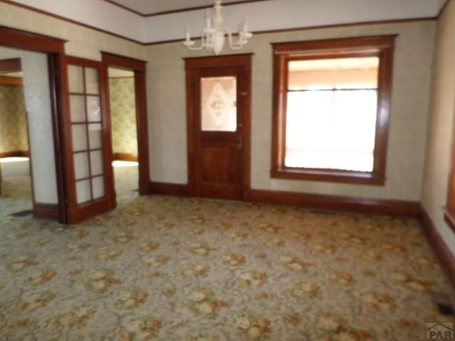 entrance foyer with a notable chandelier, baseboards, and carpet flooring