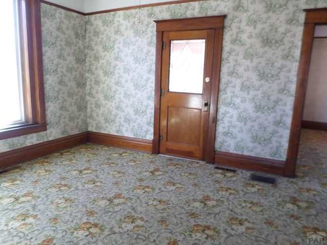 carpeted empty room featuring visible vents, baseboards, and wallpapered walls