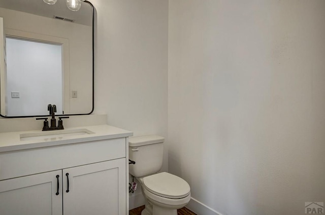 1436 Brewery Rd, Pueblo, CO 81001 - half bathroom featuring visible vents, toilet, baseboards, and vanity