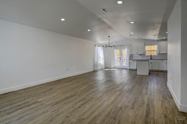 1436 Brewery Rd, Pueblo, CO 81001 - unfurnished living room with vaulted ceiling, wood finished floors, baseboards, a notable chandelier, and visible vents
