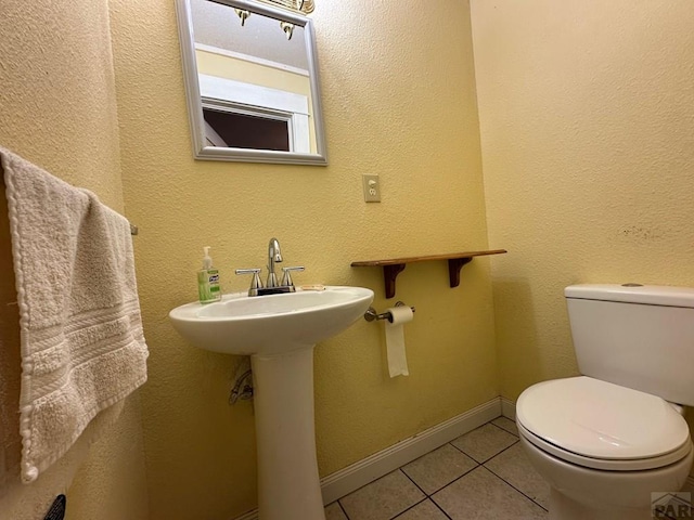 half bath featuring tile patterned flooring, baseboards, and toilet