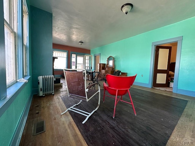 misc room featuring radiator, baseboards, visible vents, and wood finished floors