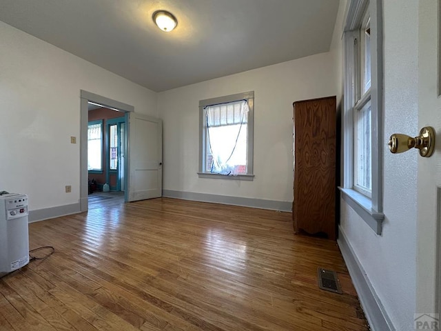 unfurnished room with visible vents, baseboards, and wood finished floors