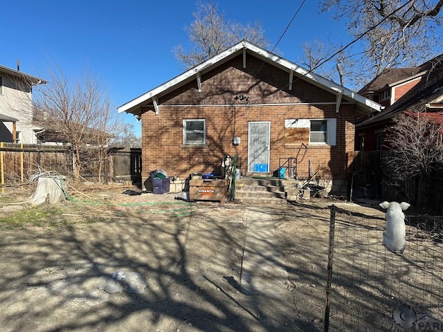 back of property with brick siding and fence