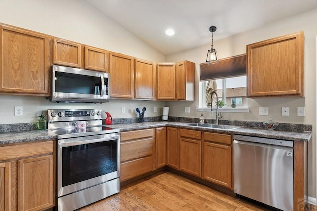 7470 Sun Prairie Dr, Fountain, CO 80925 - kitchen featuring stainless steel appliances, dark countertops, lofted ceiling, light wood-style floors, and pendant lighting