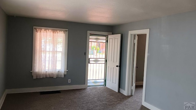 spare room with carpet, visible vents, and baseboards