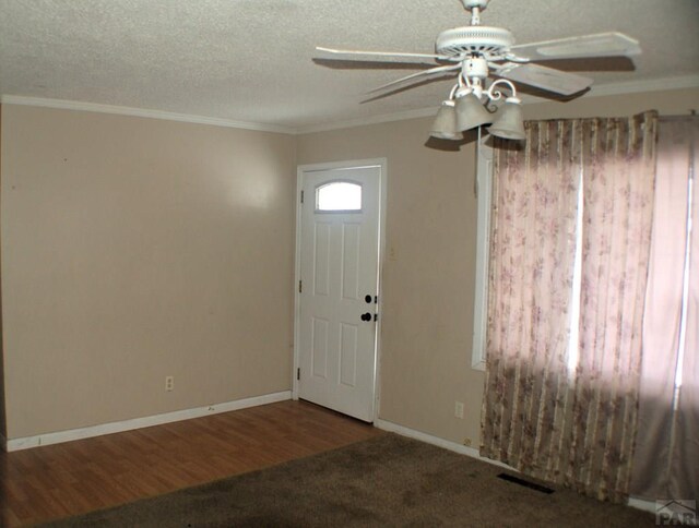 foyer featuring ornamental molding, visible vents, a textured ceiling, and baseboards