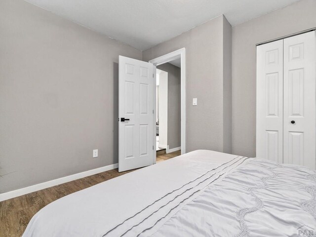 bedroom featuring dark wood-style floors, a closet, and baseboards