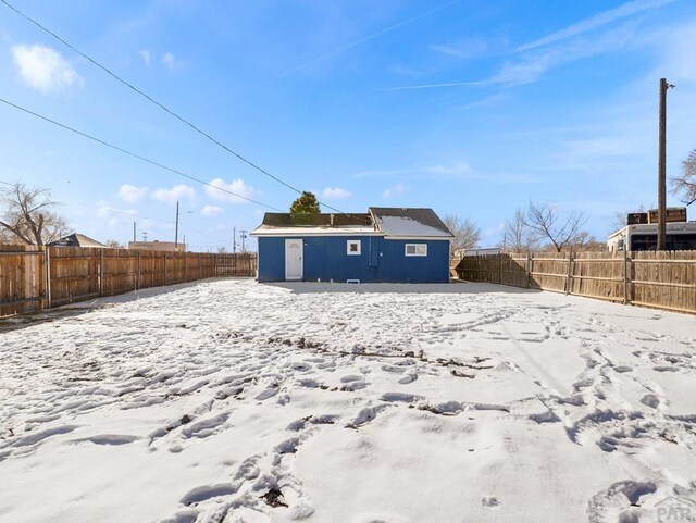 snow covered back of property featuring an outdoor structure and a fenced backyard