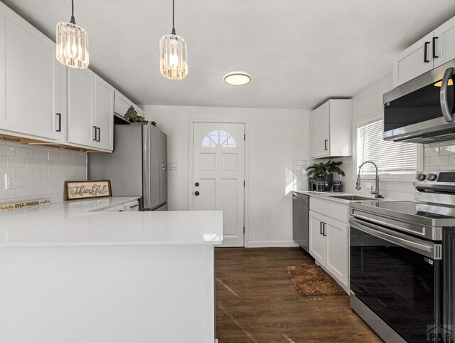 kitchen with a peninsula, dark wood-style flooring, white cabinetry, light countertops, and appliances with stainless steel finishes