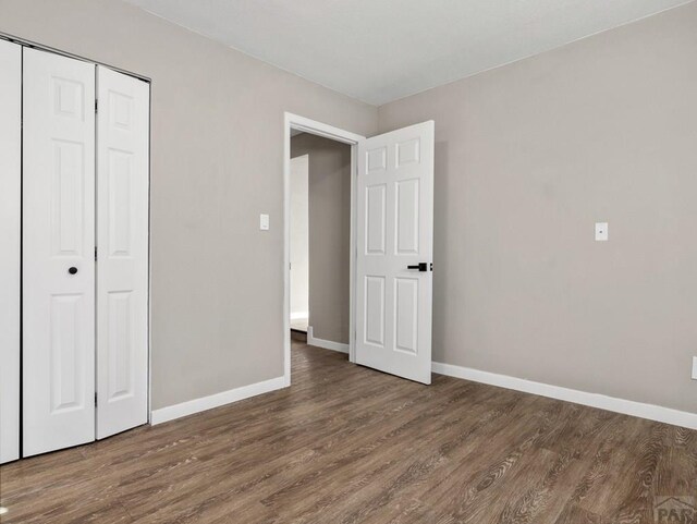 unfurnished bedroom featuring a closet, baseboards, and wood finished floors