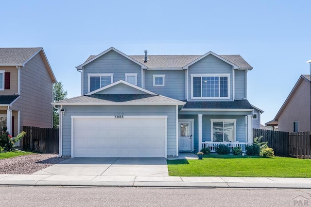 traditional-style house featuring a garage, covered porch, driveway, and fence