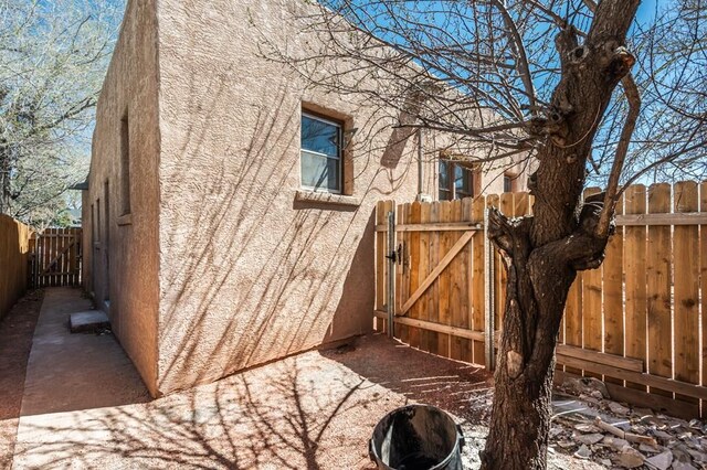 view of side of property with fence, a gate, and stucco siding