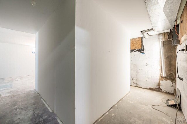 corridor featuring concrete block wall and unfinished concrete flooring