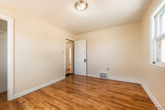 unfurnished bedroom with baseboards, visible vents, and wood finished floors