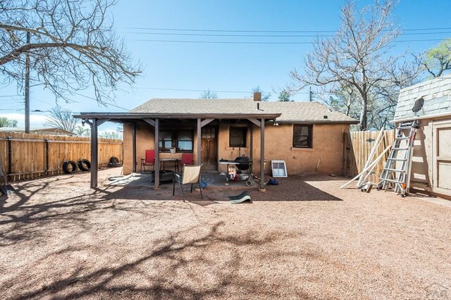 back of house with stucco siding, a fenced backyard, a shingled roof, and a patio