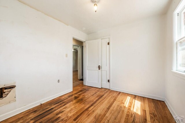 spare room featuring baseboards and wood finished floors