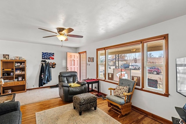 sitting room with ceiling fan, wood finished floors, and baseboards