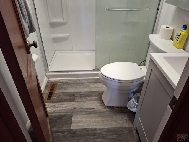 full bathroom with visible vents, toilet, a stall shower, vanity, and wood finished floors