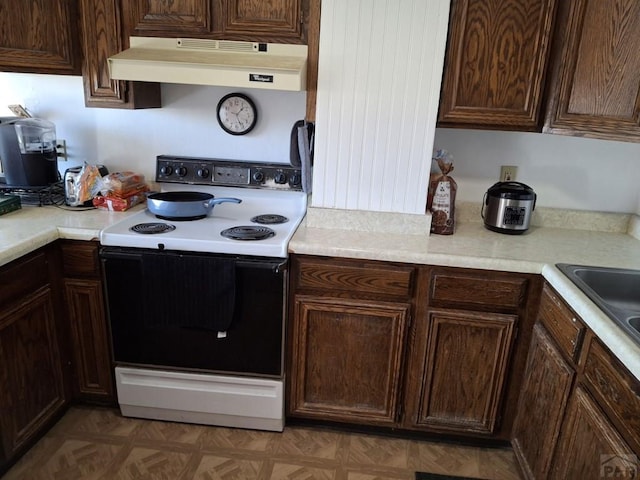 kitchen featuring light countertops, range with electric cooktop, and under cabinet range hood