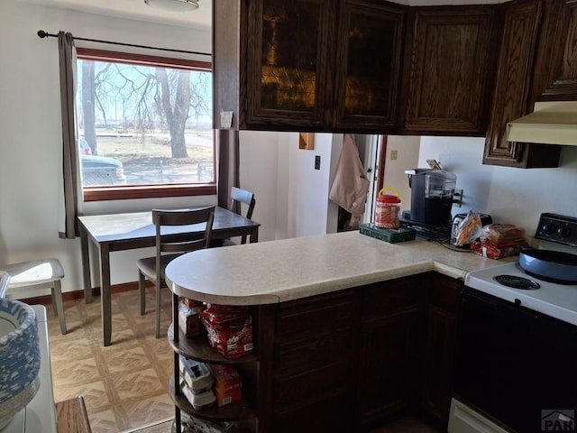 kitchen featuring dark brown cabinetry, electric range, a peninsula, ventilation hood, and light countertops