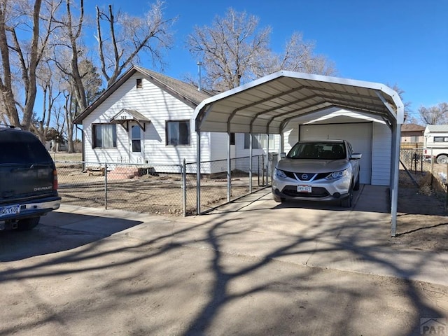 view of parking with driveway, a fenced front yard, and a detached carport