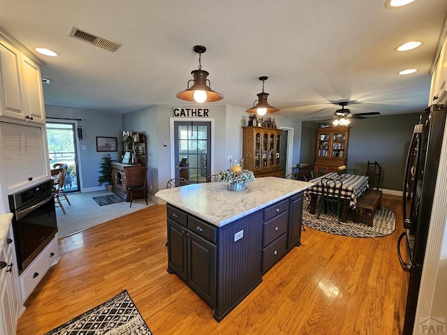 743 G St, Two Buttes, CO 81084 - kitchen featuring stainless steel oven, freestanding refrigerator, baseboards, decorative light fixtures, and light wood-type flooring