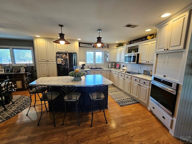 743 G St, Two Buttes, CO 81084 - kitchen featuring black appliances, a sink, a breakfast bar area, light wood-type flooring, and a center island