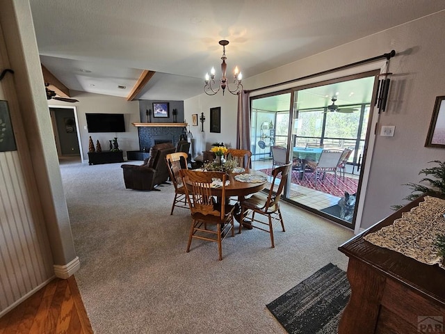 743 G St, Two Buttes, CO 81084 - carpeted dining space featuring a fireplace, baseboards, a chandelier, and vaulted ceiling