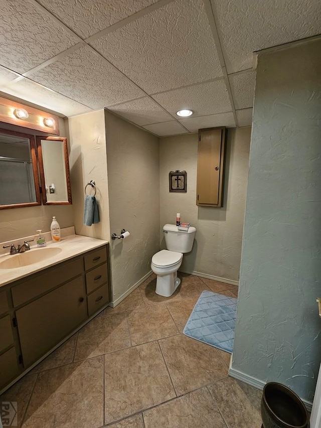 743 G St, Two Buttes, CO 81084 - bathroom featuring toilet, vanity, baseboards, a drop ceiling, and a textured wall