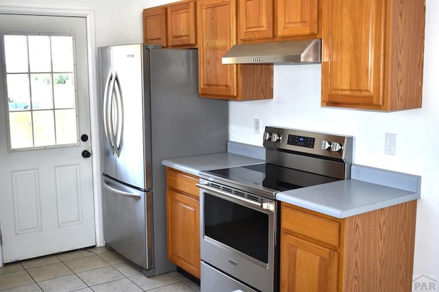 1417 Bradish Ave, La Junta, CO 81050 - kitchen featuring extractor fan, stainless steel appliances, brown cabinets, light tile patterned flooring, and light countertops