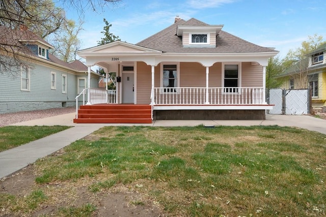 view of front of house featuring a porch, a front lawn, a chimney, and roof with shingles