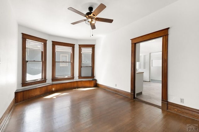 spare room featuring a ceiling fan, baseboards, and wood-type flooring