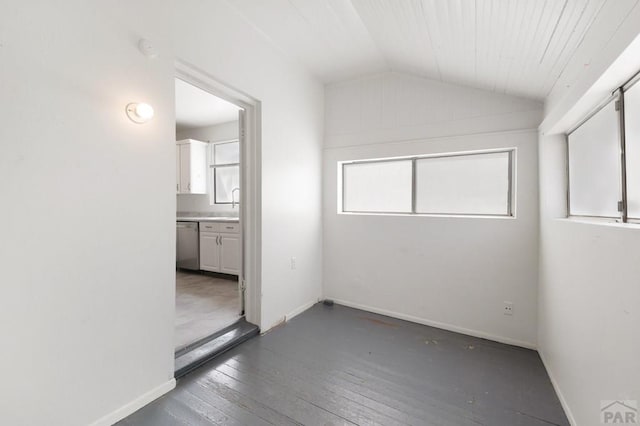 interior space featuring hardwood / wood-style floors, baseboards, and vaulted ceiling