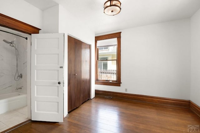 unfurnished bedroom featuring dark wood-style floors, visible vents, a closet, and baseboards