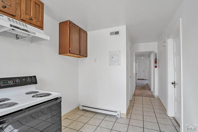 kitchen with light tile patterned floors, range with electric cooktop, brown cabinets, baseboard heating, and under cabinet range hood