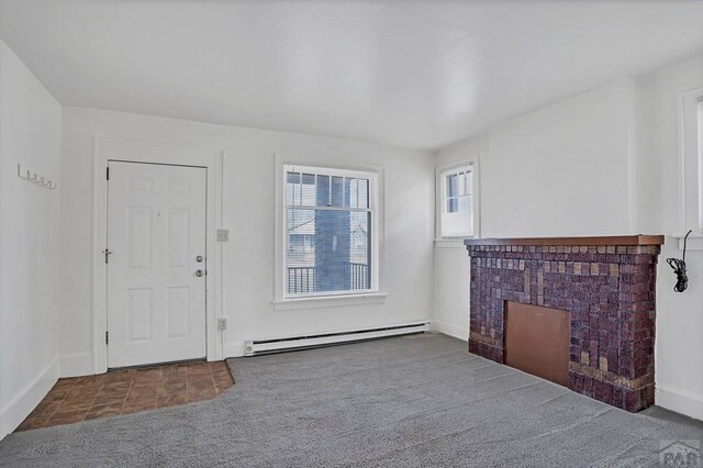 interior space with a baseboard heating unit, carpet, and baseboards