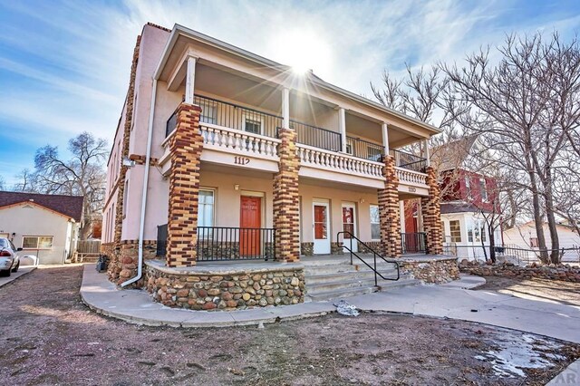 back of house with entry steps, stone siding, and stucco siding