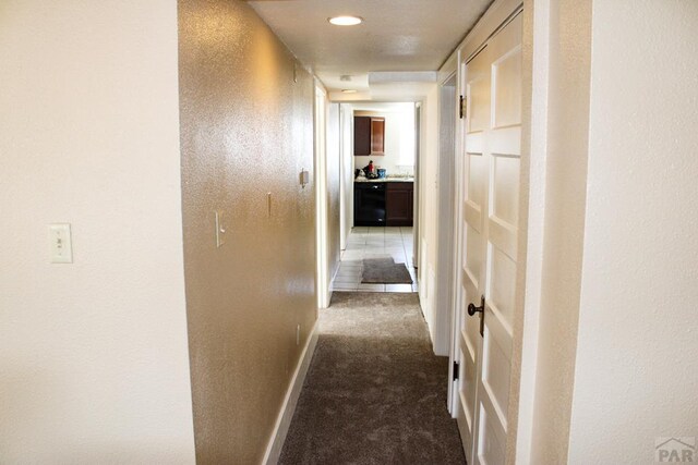 empty room with baseboards, a sink, and light colored carpet