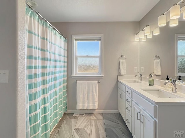 439 N Mitford Dr, Pueblo West, CO 81007 - bathroom featuring plenty of natural light, double vanity, baseboards, and a shower with curtain