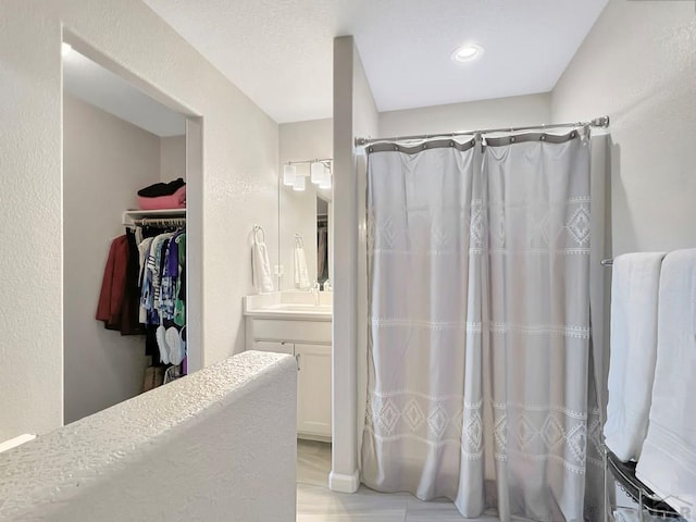 439 N Mitford Dr, Pueblo West, CO 81007 - full bath with vanity, a walk in closet, a shower with curtain, and a textured wall