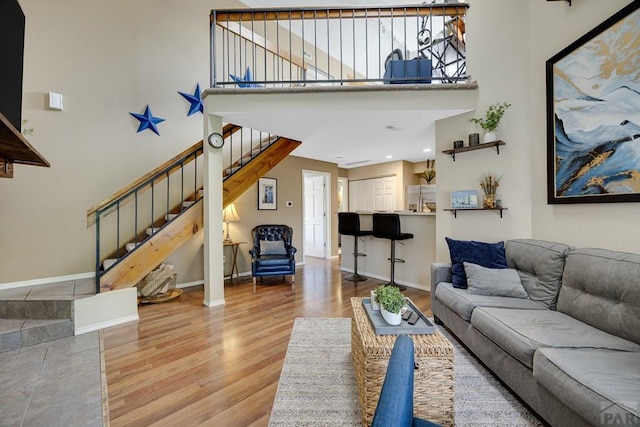 830 S Vance St, Lakewood, CO 80226 - living room with wood finished floors, a towering ceiling, stairway, and baseboards