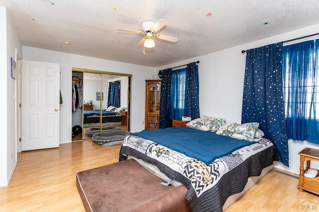 bedroom with a textured ceiling, a closet, a ceiling fan, and wood finished floors