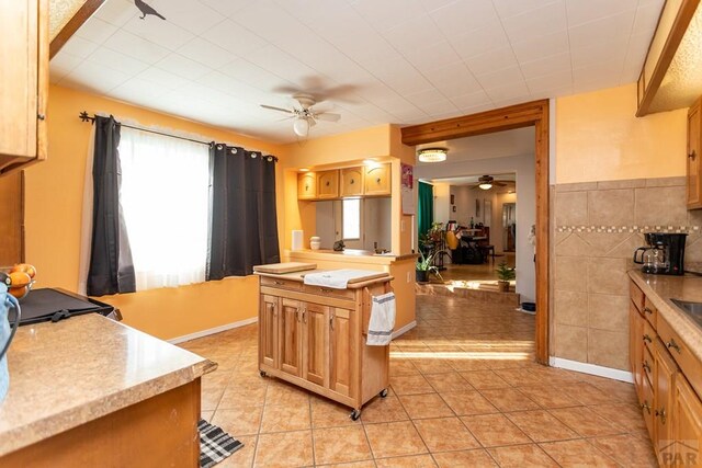 kitchen featuring light tile patterned floors, a kitchen island, light countertops, and a ceiling fan