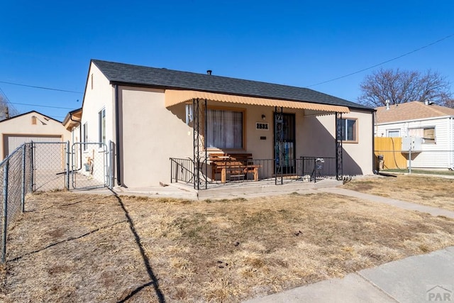 view of front facade with fence, a gate, and stucco siding